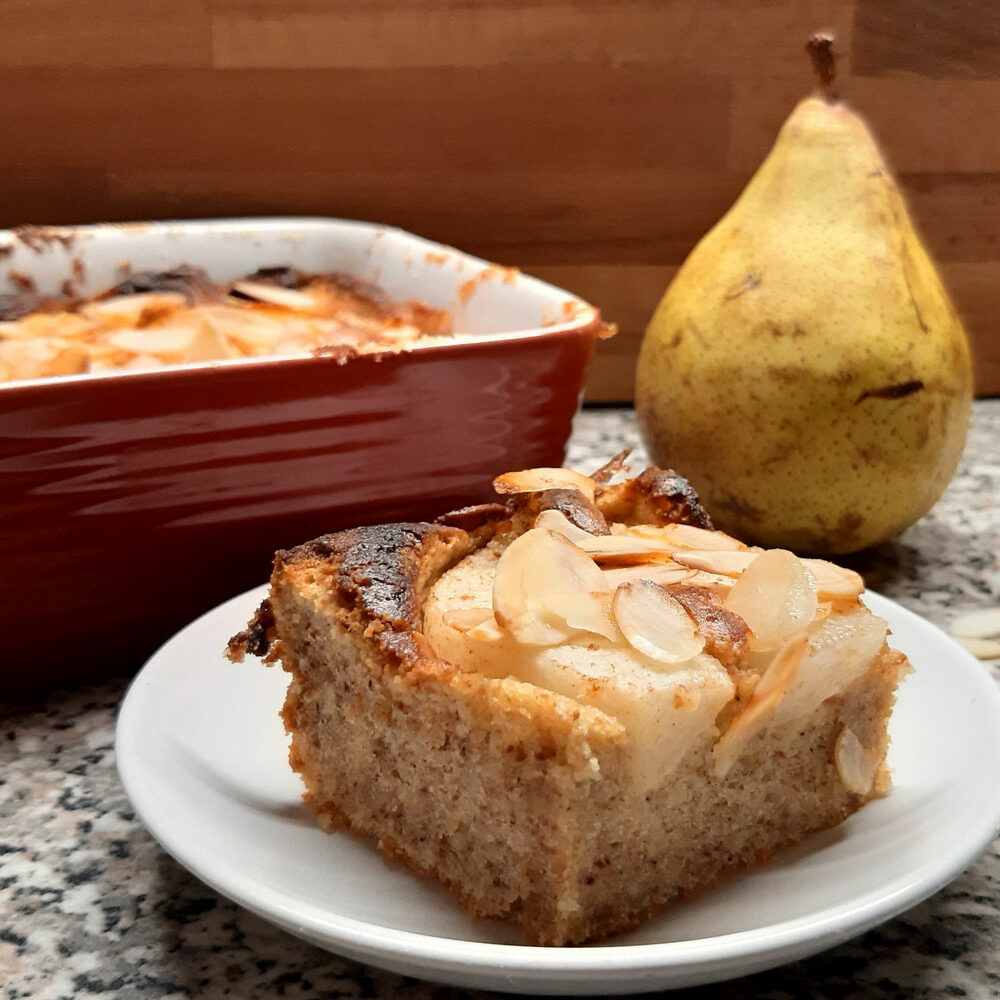 Stück Birnenkuchen mit Birne im Hintergrund